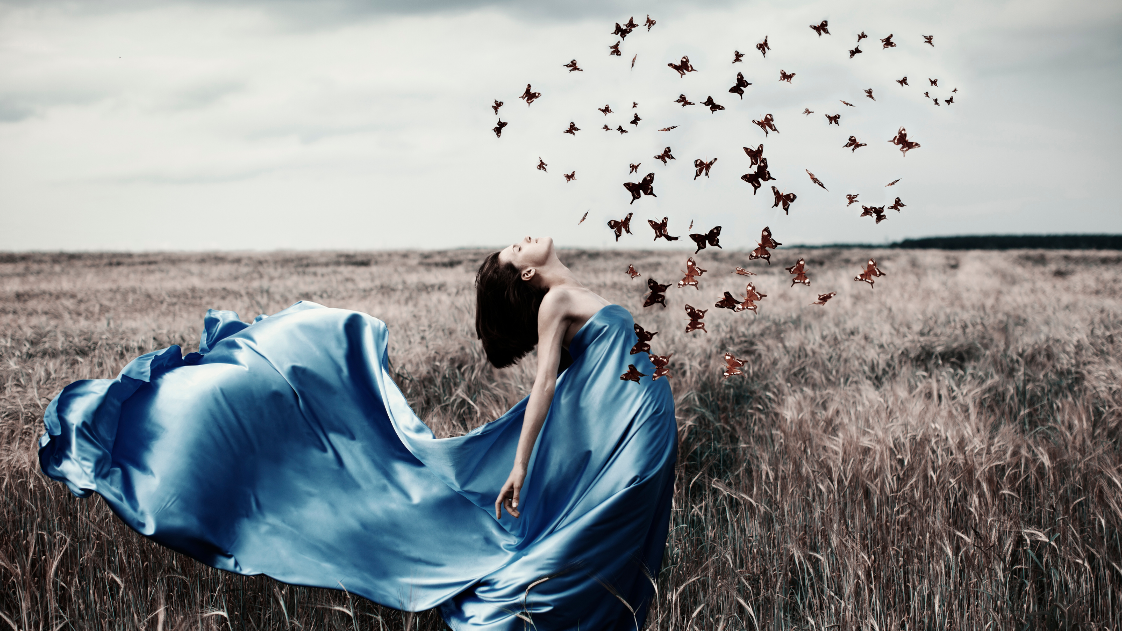 woman in blue silk dress setting butterflies free from her heart