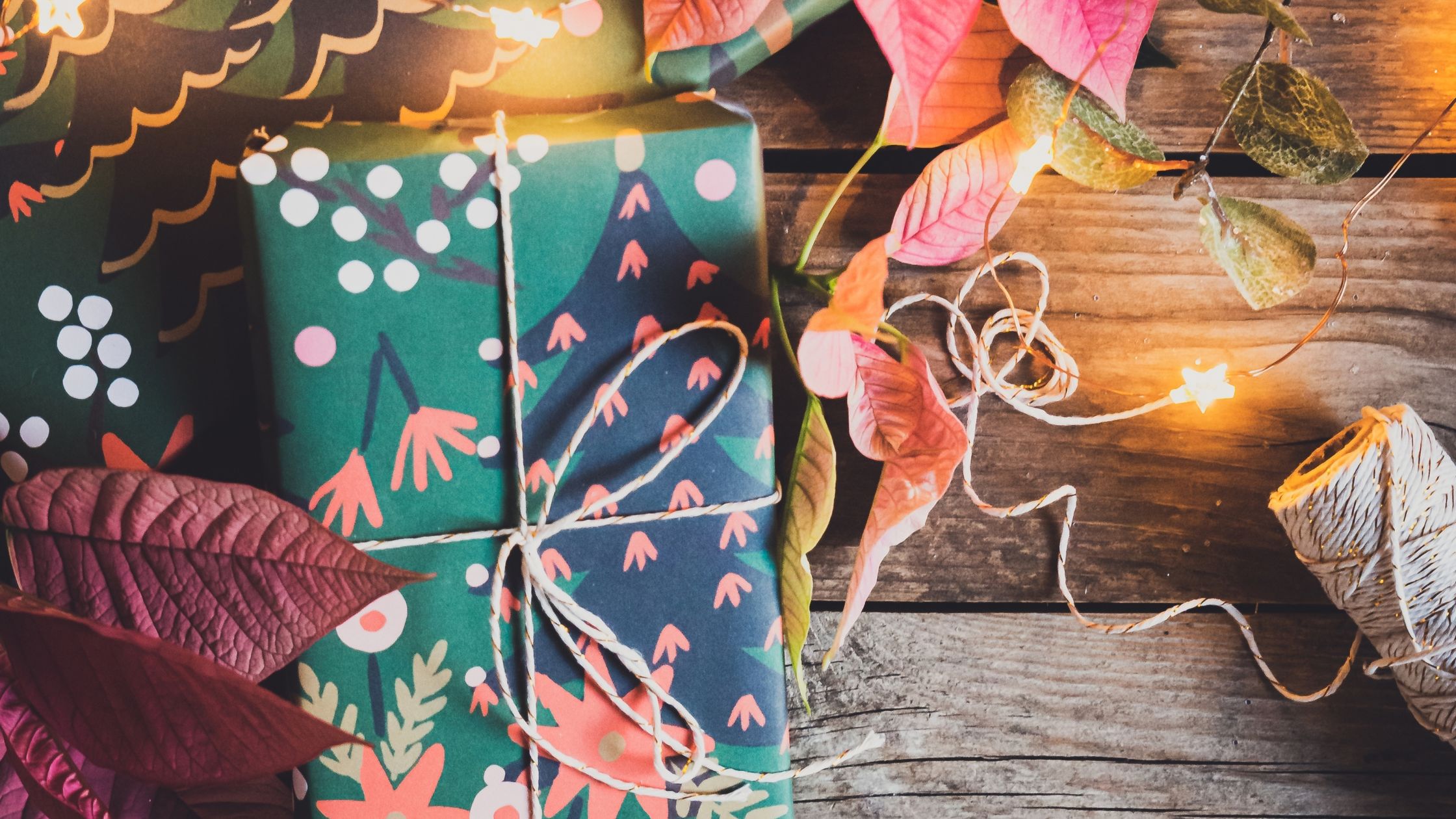 Yule gift wrapped in festive blue paper with string. String leaf lights surround scene