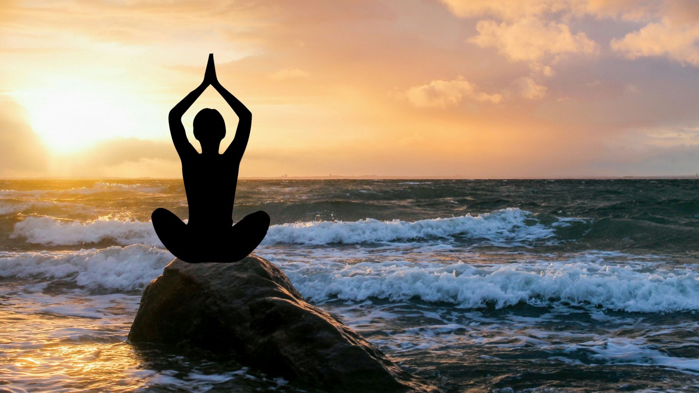 silhouette of meditator on rocks on a beach