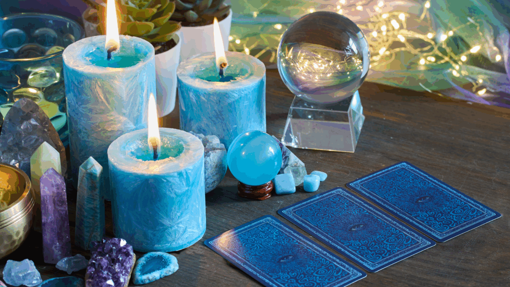 Blue oracle cards in a three card spread for a reading with blue candles burning and crystals along the border