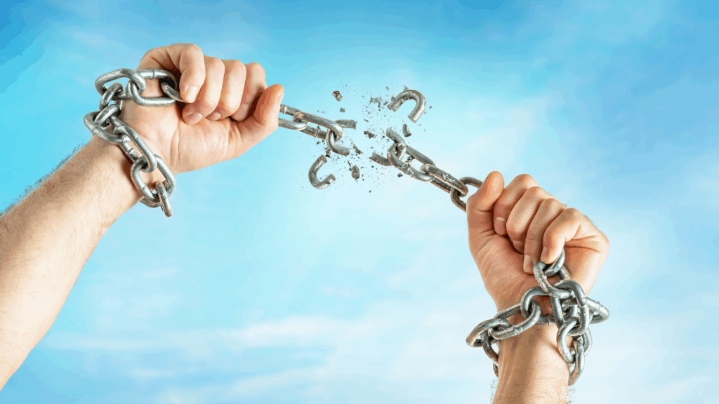 hands holding and breaking chains against a sky background