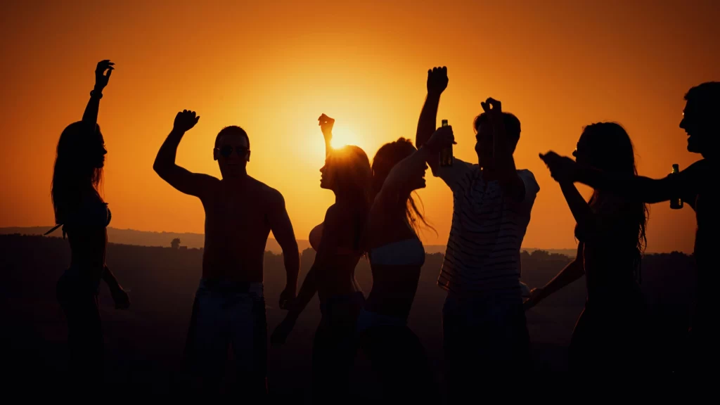 people dancing on a beach at sunset