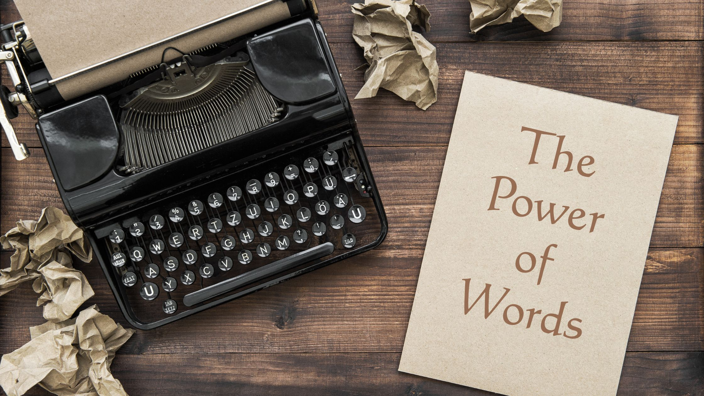 typewriter and notebook that reads "The Power of Words"