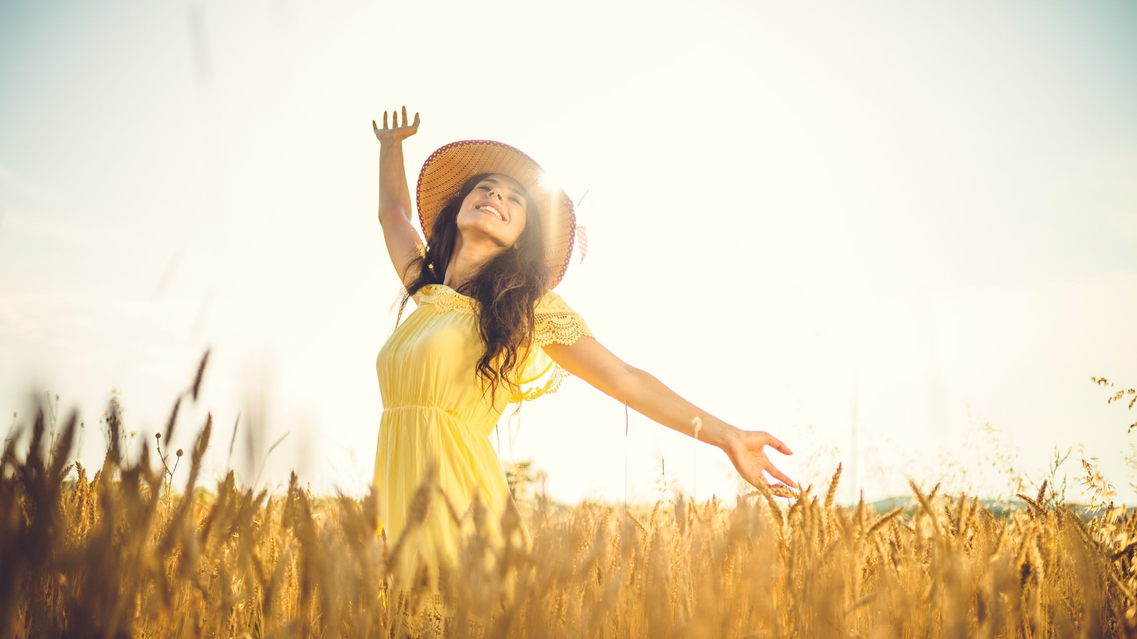 joyful woman in sunlight and yellow sundress