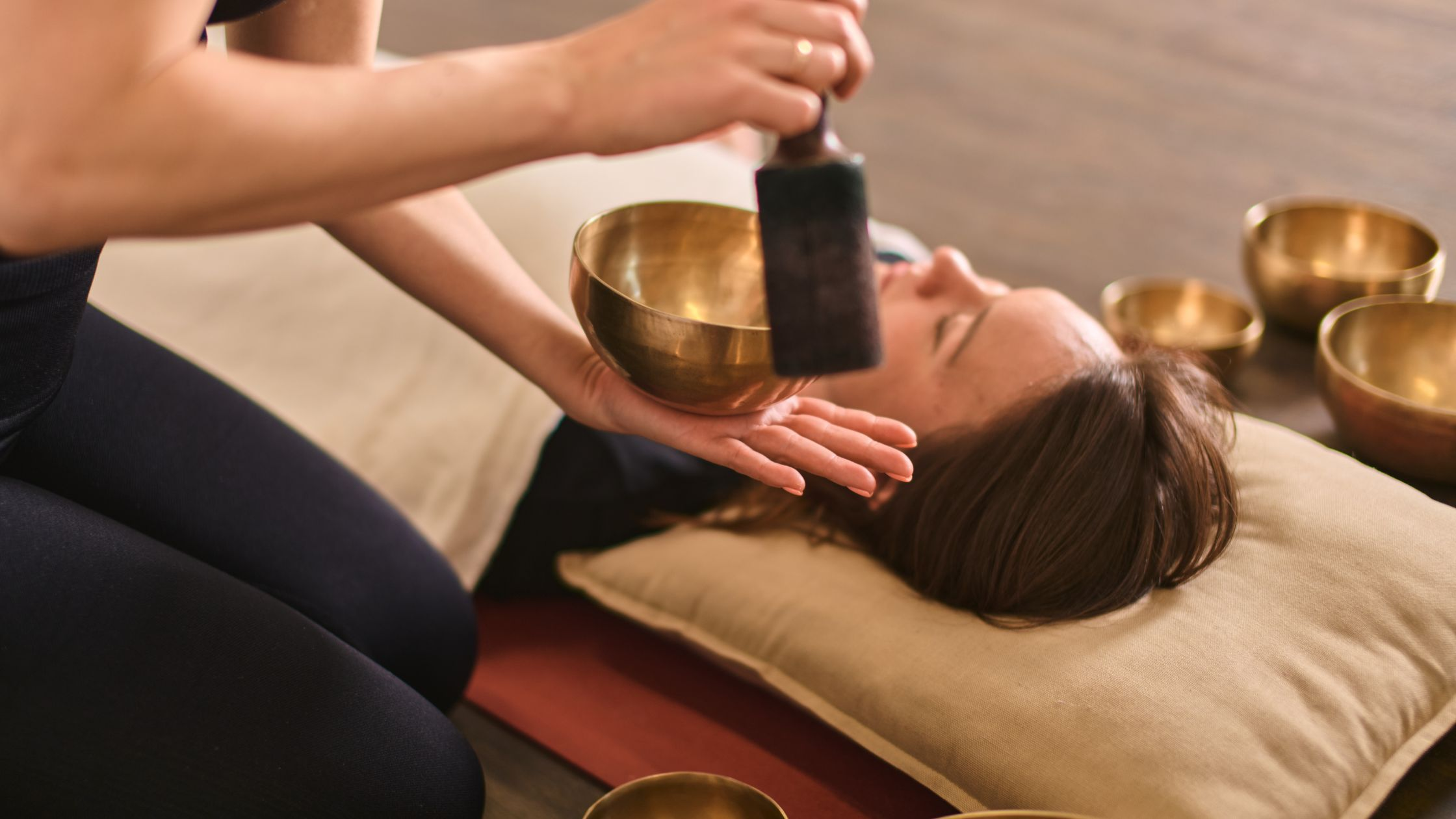person playing singing bowl above someone's head