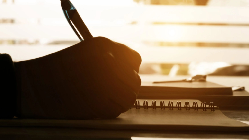 silhouette of a hand holding a pen and writing
